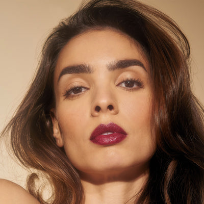 The New Vamp deep plum lipstick on model with olive skin tone. Moisturizing, nourishing, hydrating, antioxidant-rich, and botanical-infused formula.