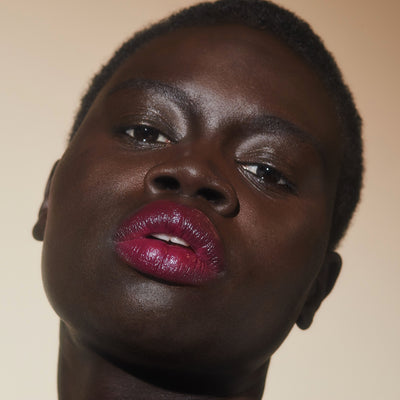 The New Vamp deep plum lipstick on model with dark skin tone. Moisturizing, nourishing, hydrating, antioxidant-rich, and botanical-infused formula.