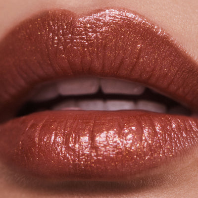 Public burnt orange shimmer lipstick on model with olive skin tone. Moisturizing, nourishing, hydrating, antioxidant-rich, and botanical-infused formula.