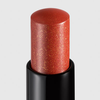 Public burnt orange shimmer lipstick product shot close up. Moisturizing, nourishing, hydrating, antioxidant-rich, and botanical-infused formula.