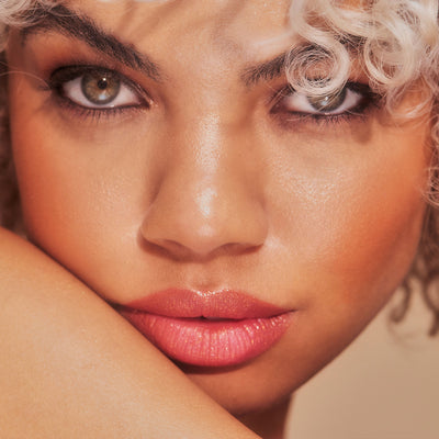 Public burnt orange shimmer lipstick on model with medium skin tone. Moisturizing, nourishing, hydrating, antioxidant-rich, and botanical-infused formula.